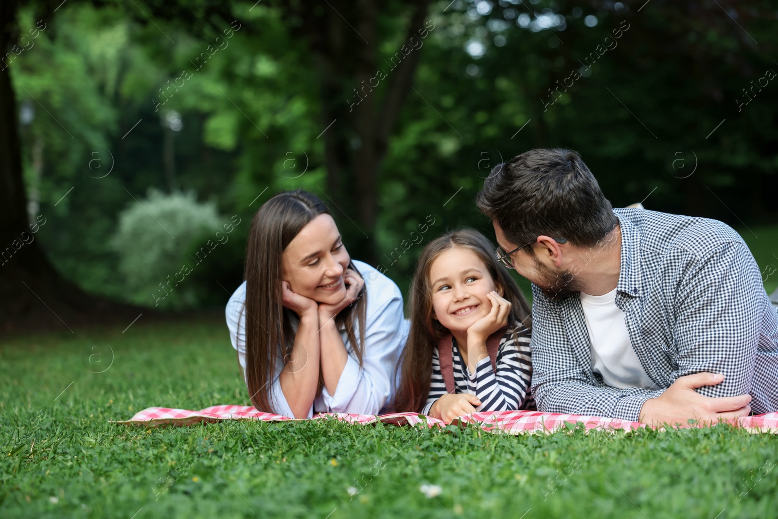 Happy family spending time together on checkered picnic blanket outdoors Photo of Happy family spending time together on checkered picnic blanket outdoors