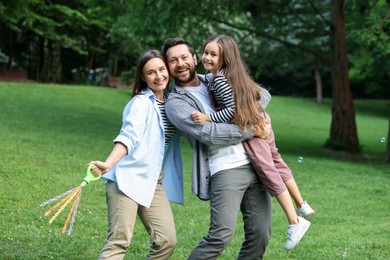Photo of Family portrait of smiling parents and daughter outdoors