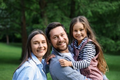 Photo of Family portrait of smiling parents and daughter outdoors