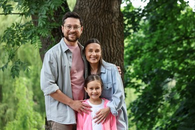 Photo of Family portrait of smiling parents and daughter outdoors