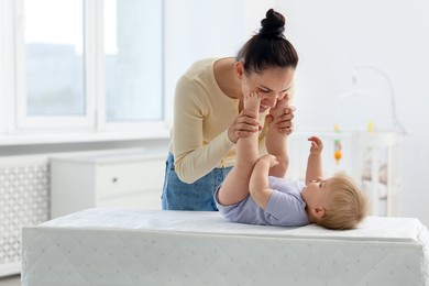 Photo of Mother playing with her cute baby on changing table at home