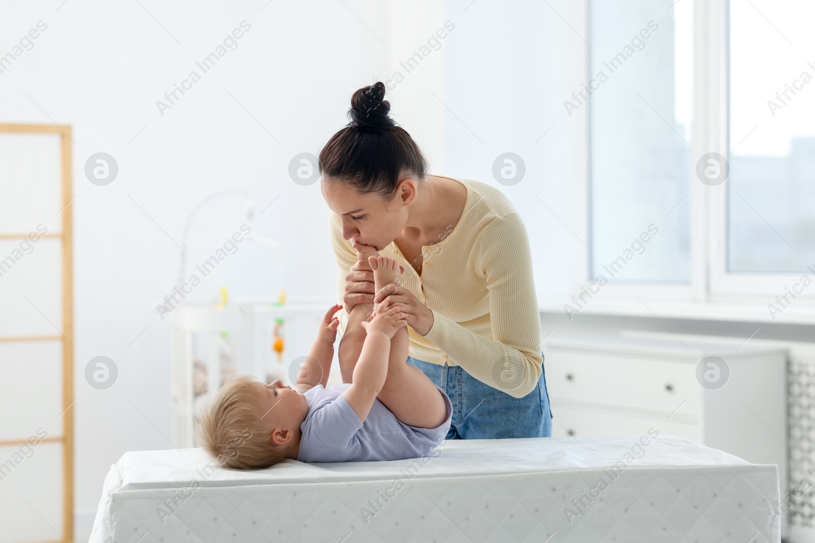Mother playing with her cute baby on changing table at home Photo of Mother playing with her cute baby on changing table at home