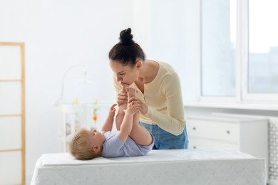 Photo of Mother playing with her cute baby on changing table at home
