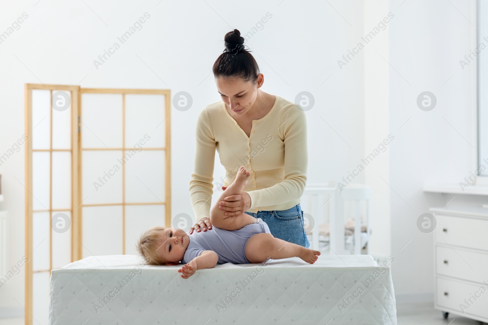 Mother playing with her cute baby on changing table at home Photo of Mother playing with her cute baby on changing table at home