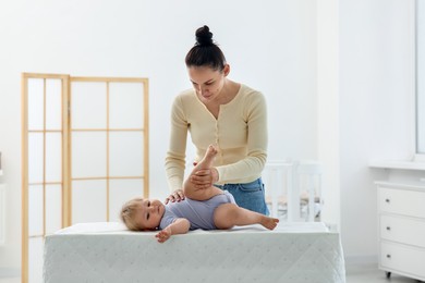 Photo of Mother playing with her cute baby on changing table at home