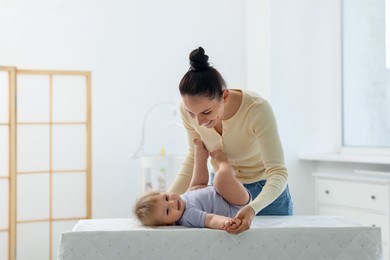 Photo of Mother playing with her cute baby on changing table at home