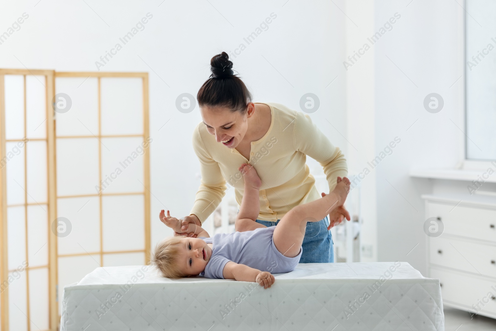 Mother playing with her cute baby on changing table at home Photo of Mother playing with her cute baby on changing table at home