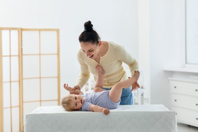 Photo of Mother playing with her cute baby on changing table at home