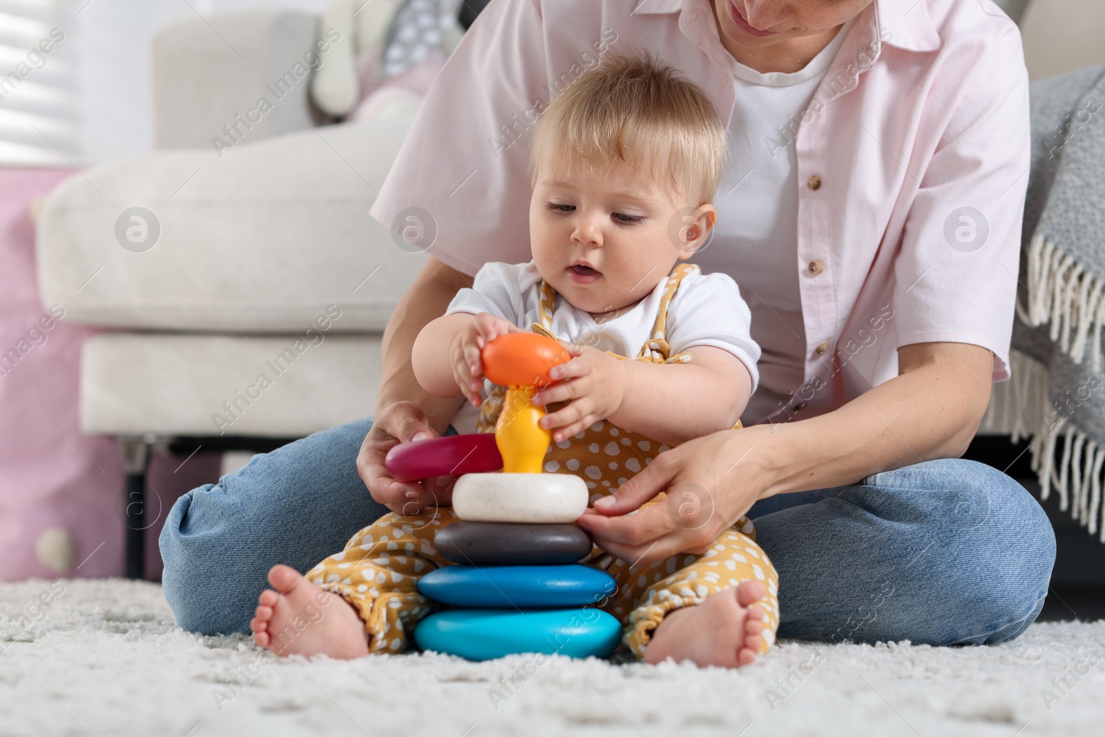 Mother and her little baby playing with toy pyramid on floor at home, closeup Photo of Mother and her little baby playing with toy pyramid on floor at home, closeup