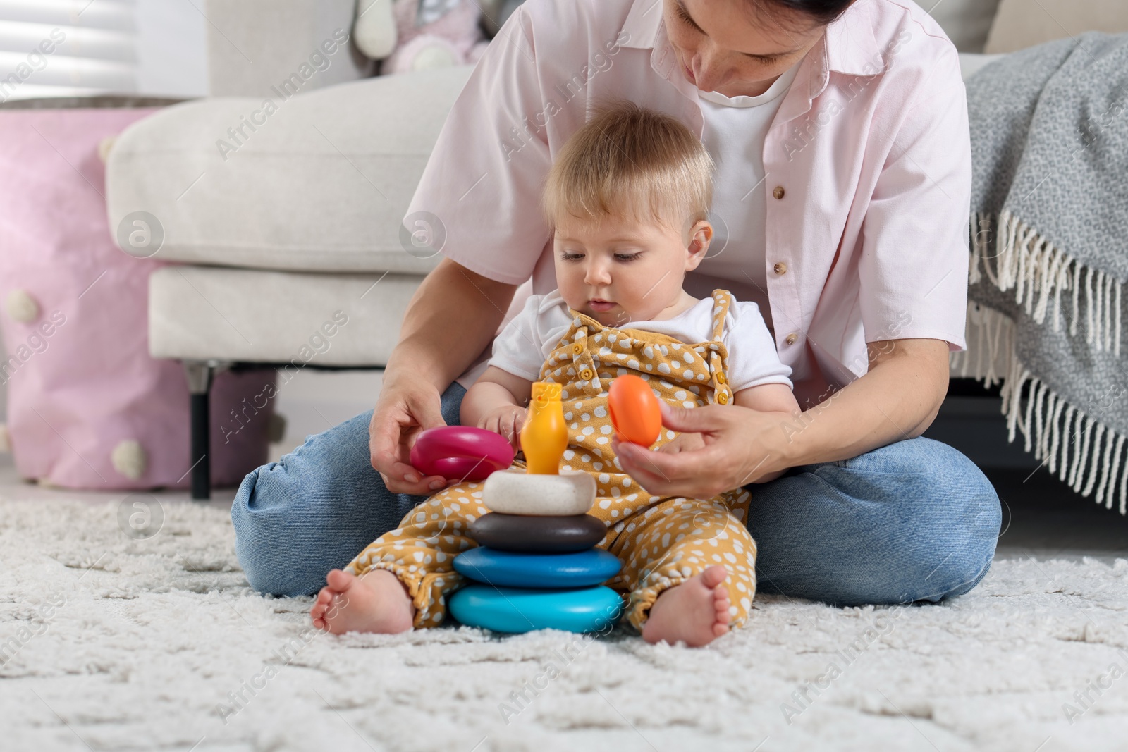 Mother and her little baby playing with toy pyramid on floor at home Photo of Mother and her little baby playing with toy pyramid on floor at home