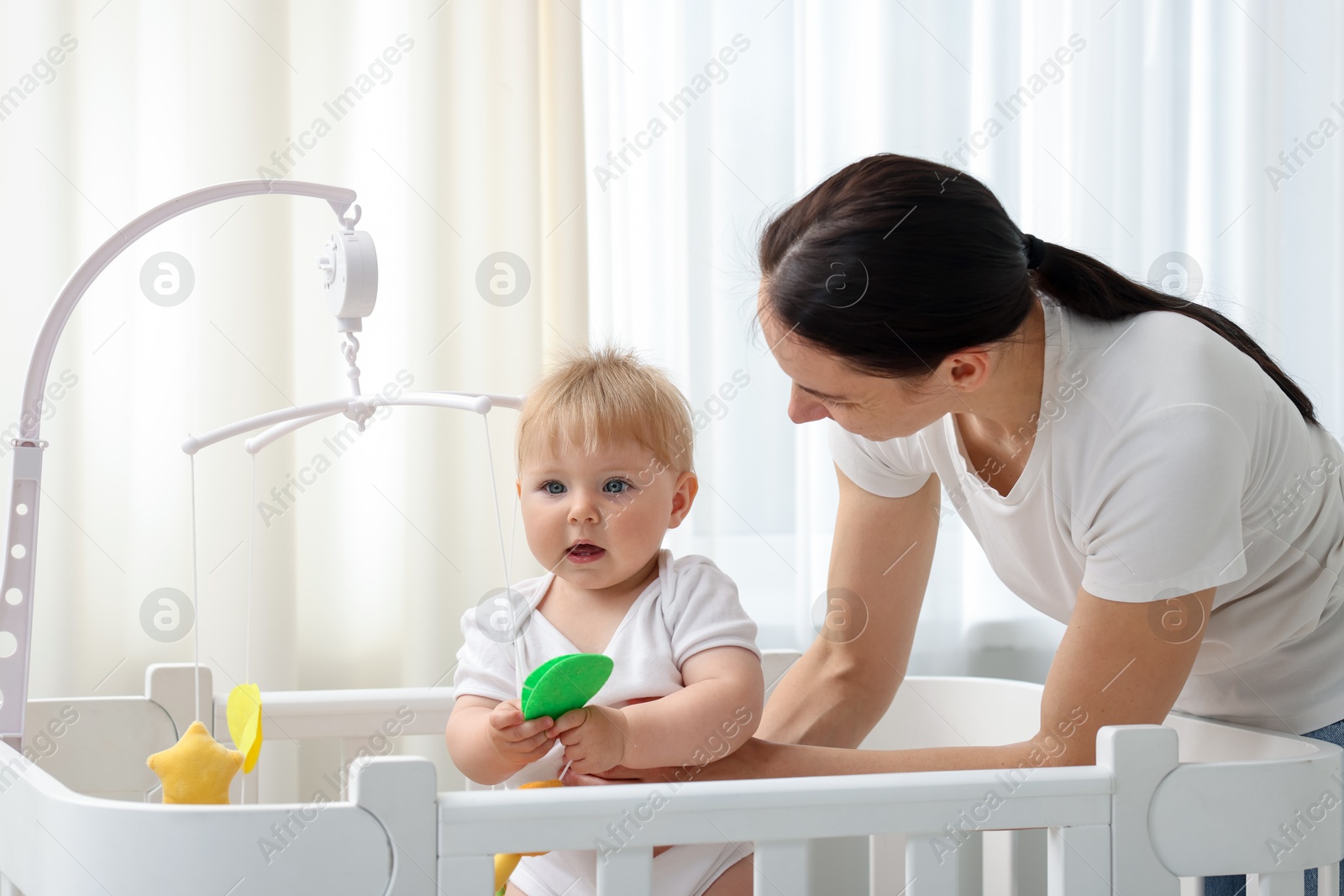 Mother playing with her cute baby in crib at home Photo of Mother playing with her cute baby in crib at home
