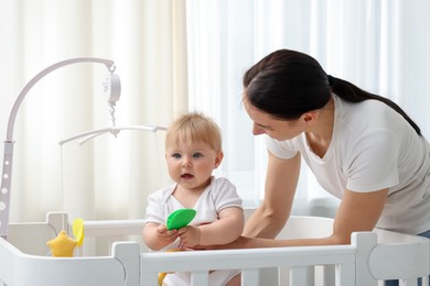 Photo of Mother playing with her cute baby in crib at home