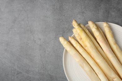 Photo of Raw white asparagus spears on grey textured table, top view. Space for text