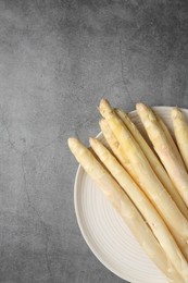 Photo of Raw white asparagus spears on grey textured table, top view. Space for text