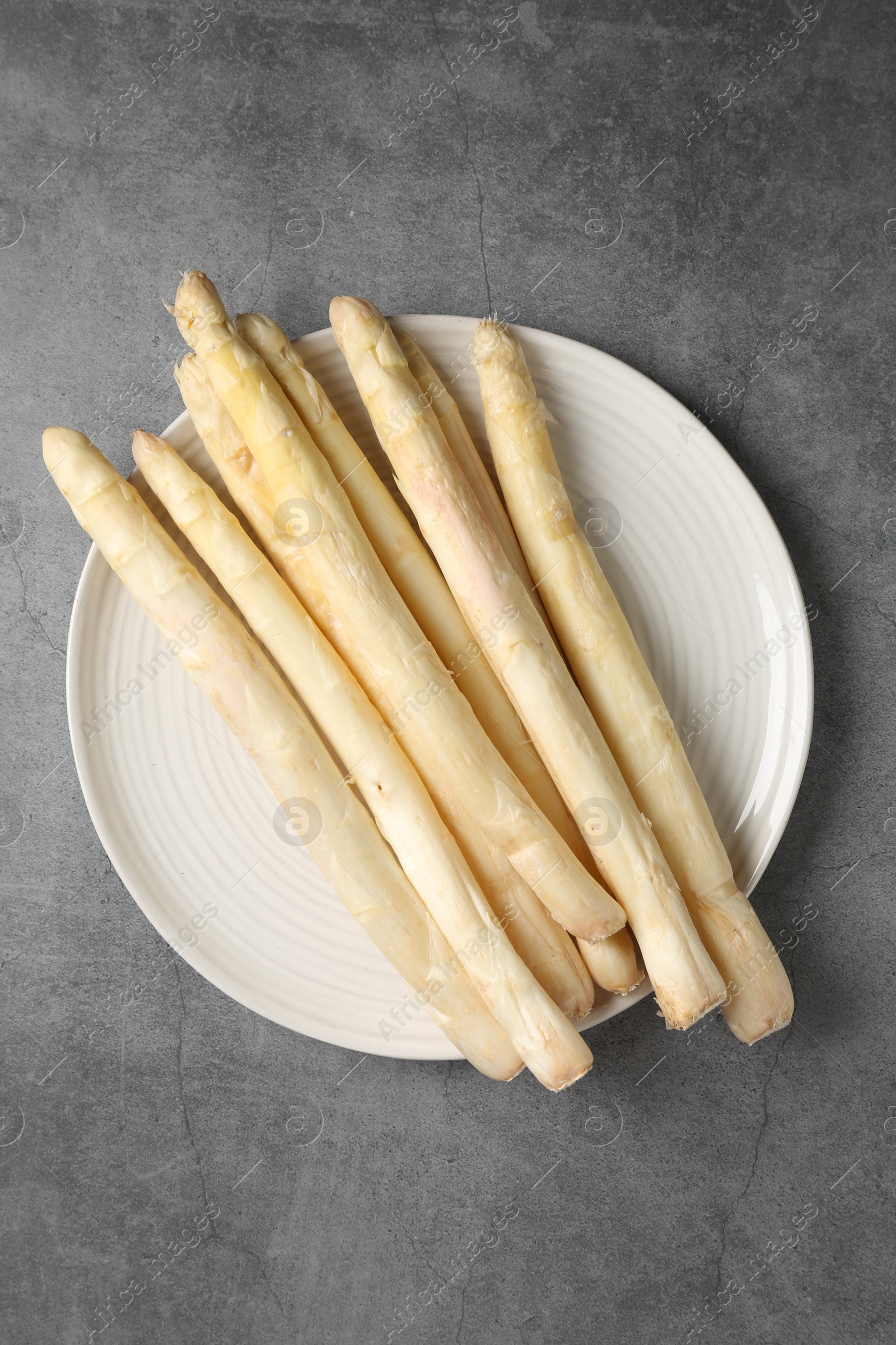 Raw white asparagus spears on grey textured table, top view Photo of Raw white asparagus spears on grey textured table, top view