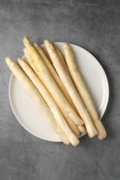 Photo of Raw white asparagus spears on grey textured table, top view