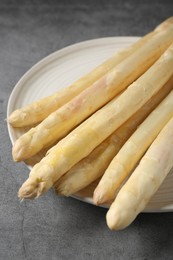 Photo of Raw white asparagus spears on grey textured table, closeup