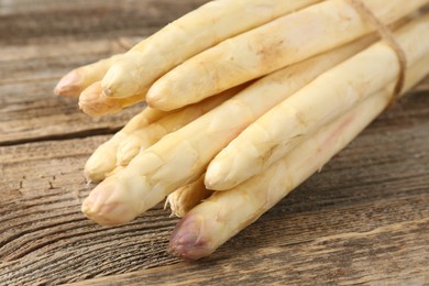 Photo of Raw white asparagus spears on wooden table, closeup
