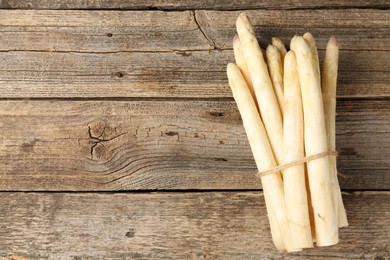 Photo of Bunch of raw white asparagus spears on wooden table, top view. Space for text