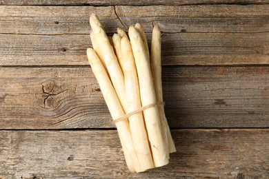Photo of Bunch of raw white asparagus spears on wooden table, top view