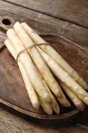 Photo of Raw white asparagus spears on wooden table, closeup
