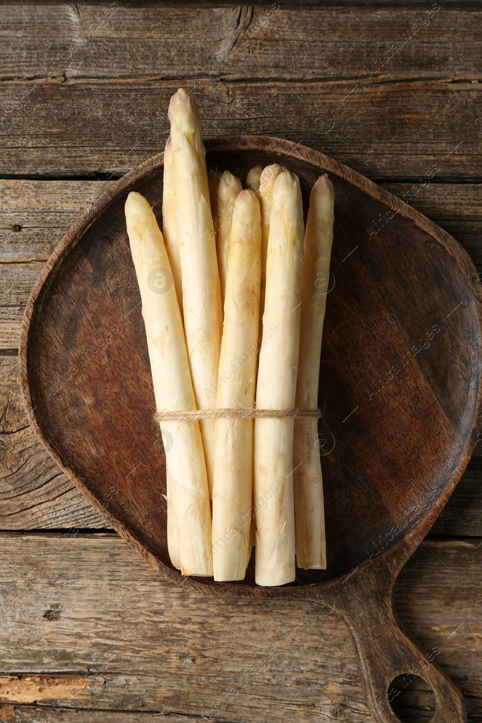 Photo of Bunch of raw white asparagus spears on wooden table, top view