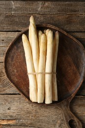 Photo of Bunch of raw white asparagus spears on wooden table, top view