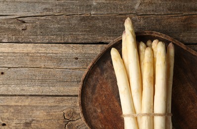 Photo of Bunch of raw white asparagus spears on wooden table, top view. Space for text