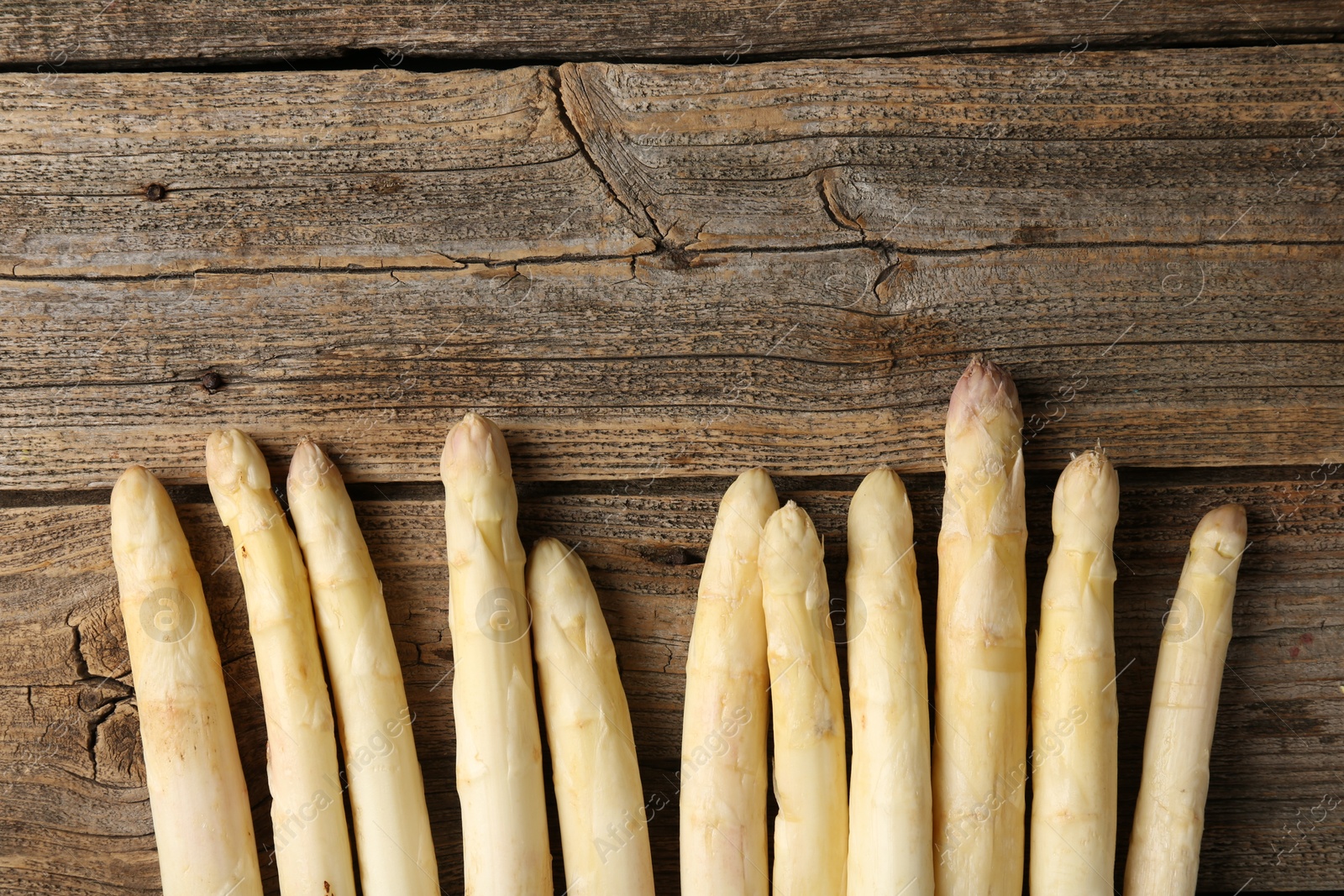 Raw white asparagus spears on wooden table, flat lay. Space for text Photo of Raw white asparagus spears on wooden table, flat lay. Space for text