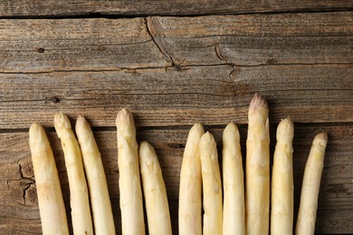 Photo of Raw white asparagus spears on wooden table, flat lay. Space for text