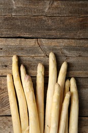 Photo of Raw white asparagus spears on wooden table, flat lay. Space for text