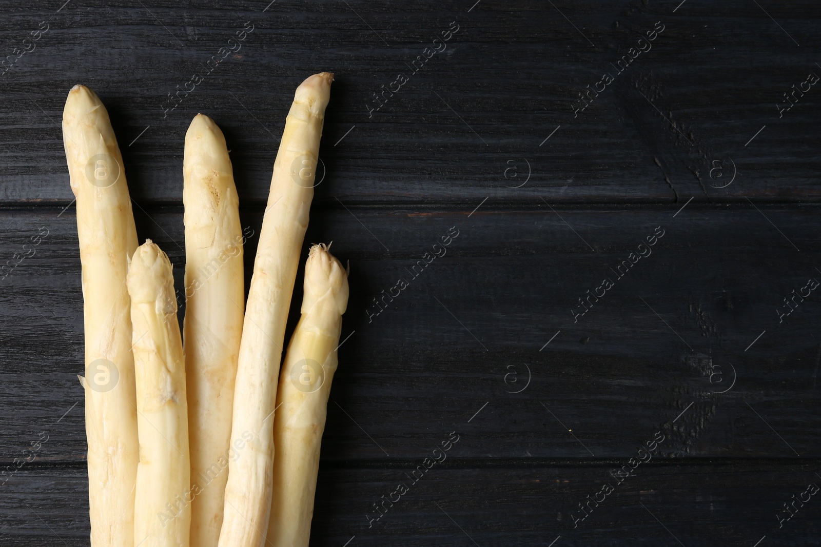 Raw white asparagus spears on black wooden table, flat lay. Space for text Photo of Raw white asparagus spears on black wooden table, flat lay. Space for text