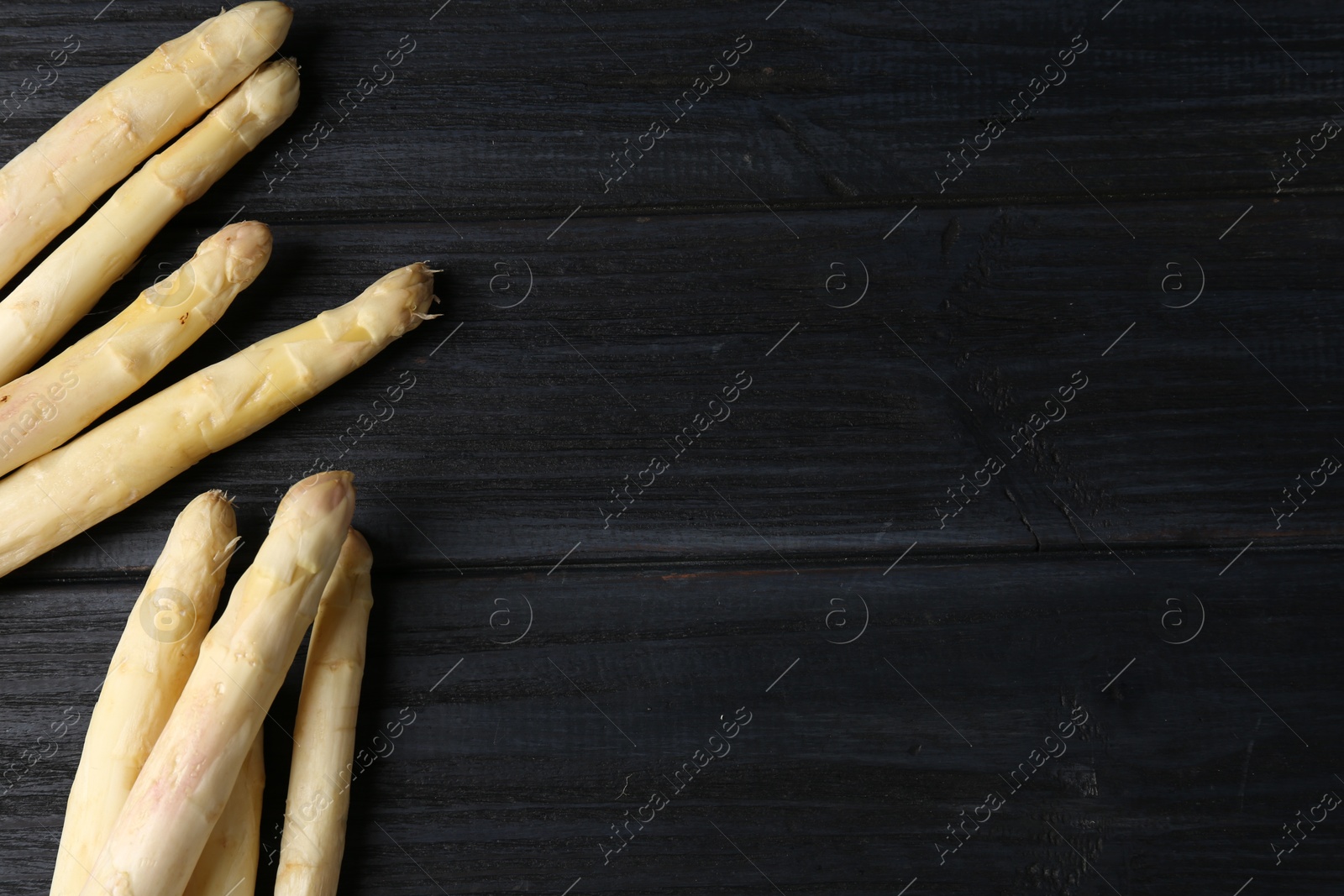 Raw white asparagus spears on black wooden table, flat lay. Space for text Photo of Raw white asparagus spears on black wooden table, flat lay. Space for text