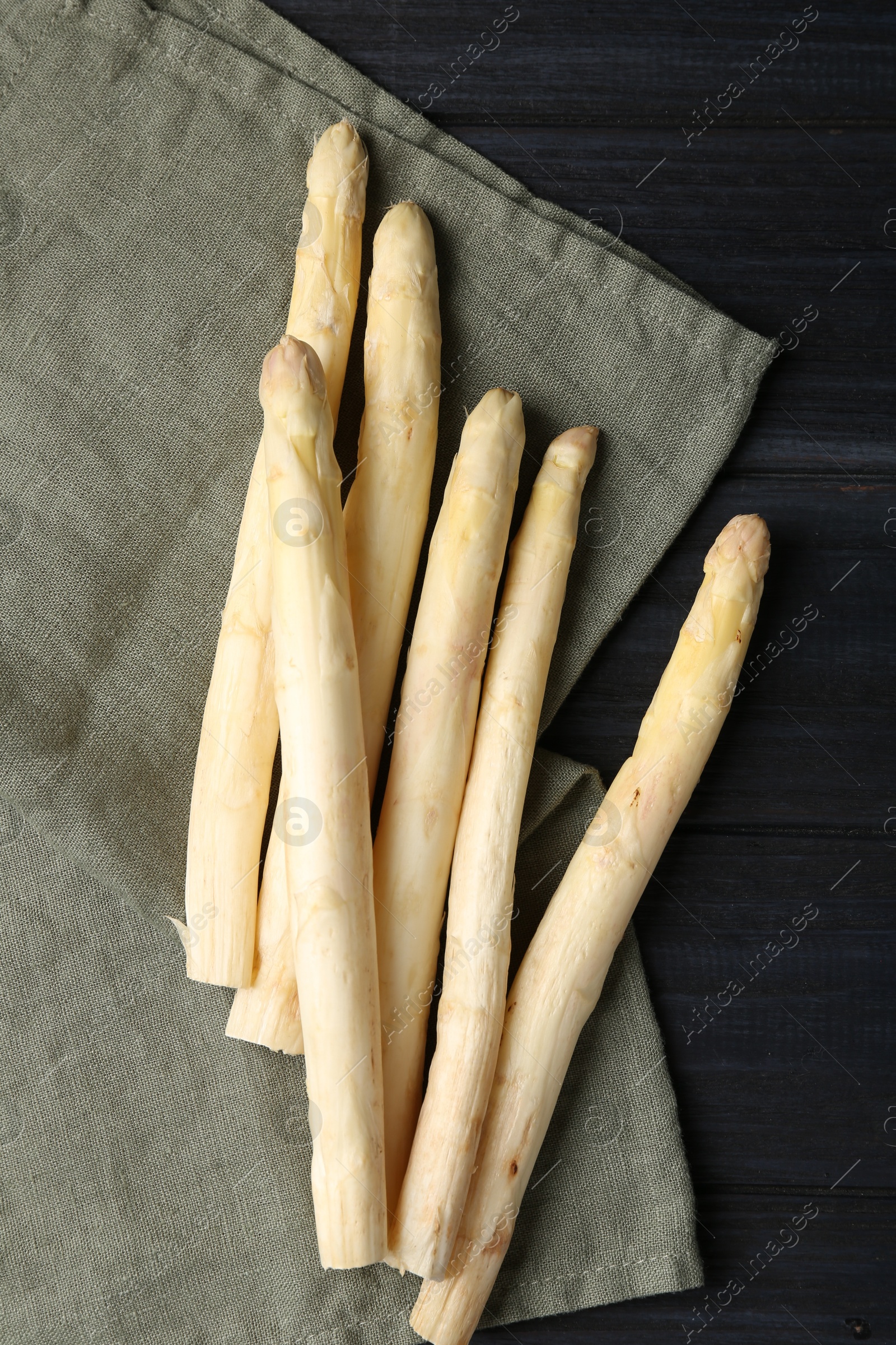Raw white asparagus spears on black wooden table, flat lay Photo of Raw white asparagus spears on black wooden table, flat lay