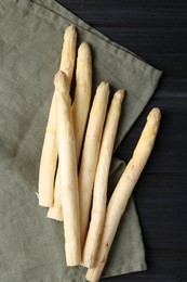 Photo of Raw white asparagus spears on black wooden table, flat lay