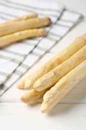 Photo of Raw asparagus spears on white wooden table, closeup
