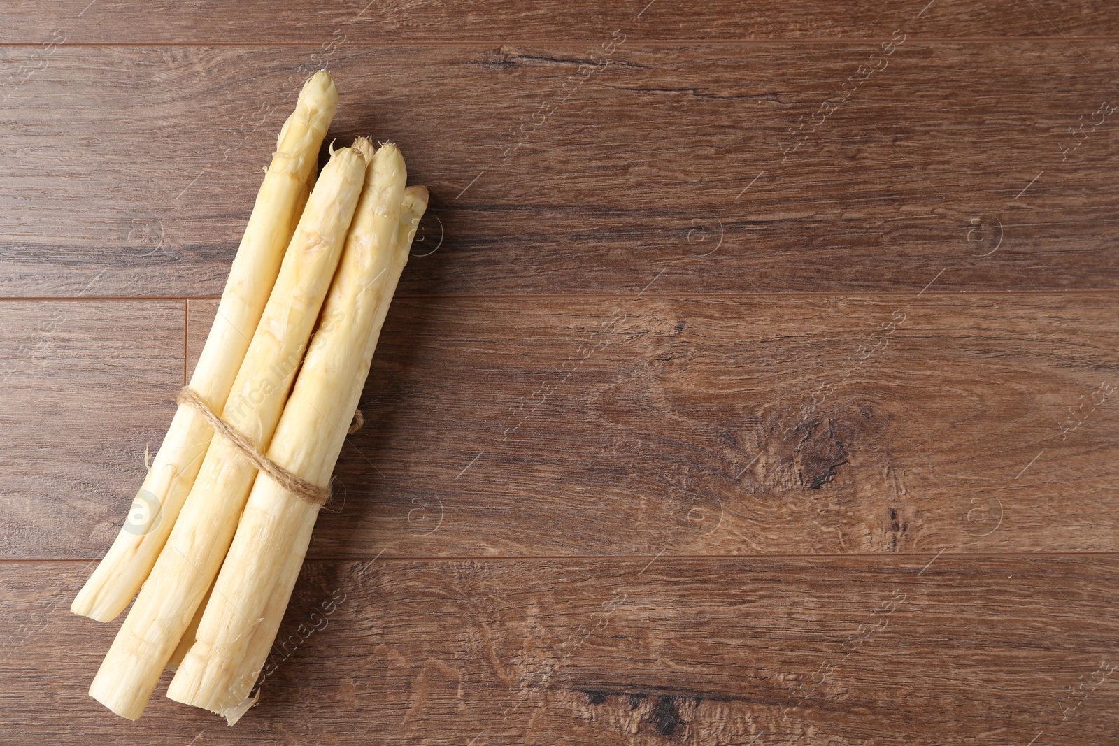 Bunch of raw white asparagus spears on wooden table, top view. Space for text Photo of Bunch of raw white asparagus spears on wooden table, top view. Space for text