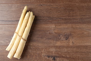 Photo of Bunch of raw white asparagus spears on wooden table, top view. Space for text