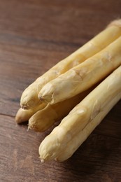 Photo of Raw white asparagus spears on wooden table, closeup