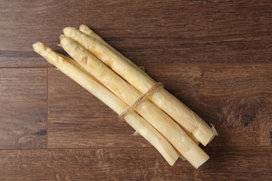 Photo of Bunch of raw white asparagus spears on wooden table, top view