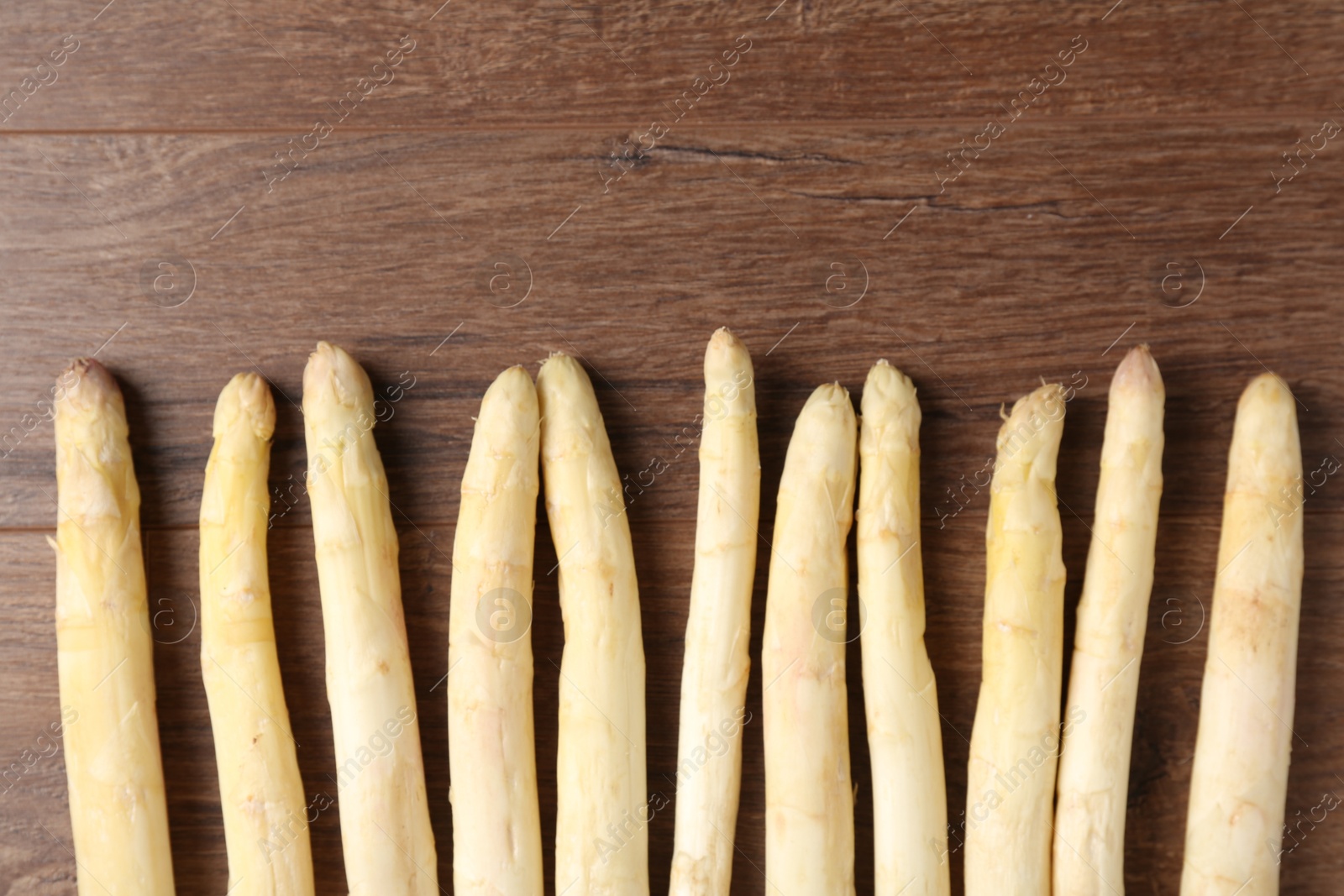 Raw white asparagus spears on wooden table, flat lay. Space for text Photo of Raw white asparagus spears on wooden table, flat lay. Space for text