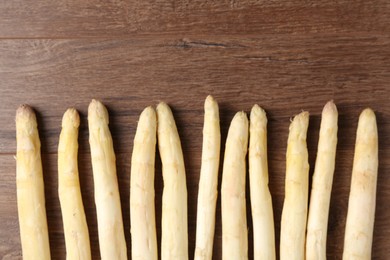 Photo of Raw white asparagus spears on wooden table, flat lay. Space for text