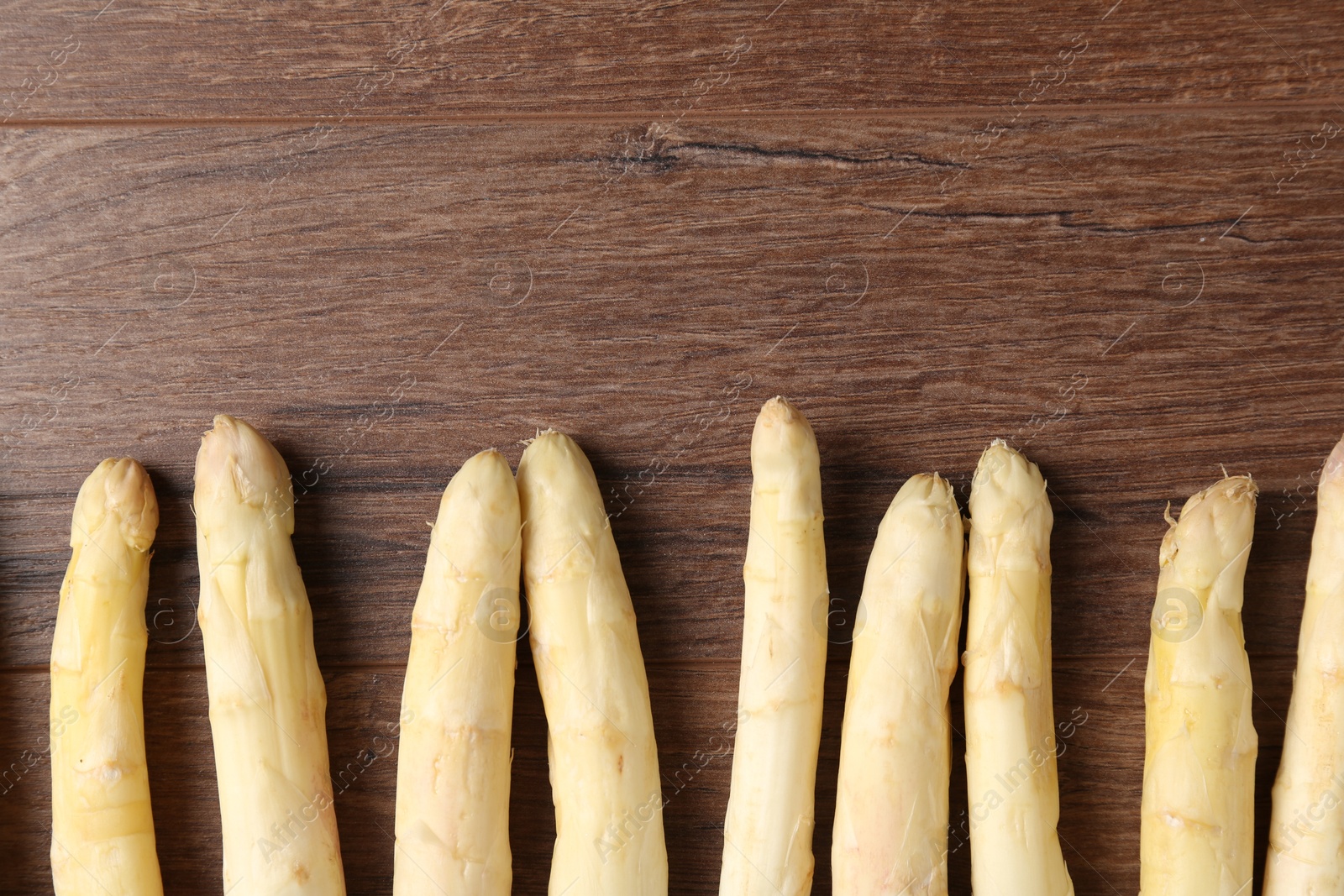 Raw white asparagus spears on wooden table, flat lay. Space for text Photo of Raw white asparagus spears on wooden table, flat lay. Space for text