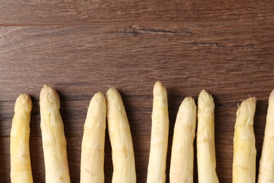 Photo of Raw white asparagus spears on wooden table, flat lay. Space for text