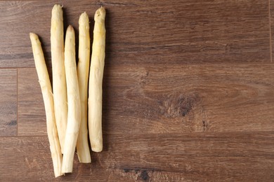 Photo of Raw white asparagus spears on wooden table, flat lay. Space for text