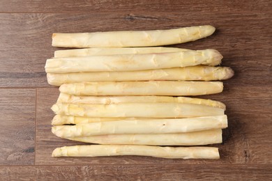 Photo of Raw white asparagus spears on wooden table, top view