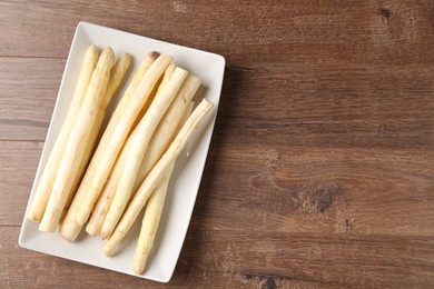 Photo of Raw white asparagus spears on wooden table, top view. Space for text