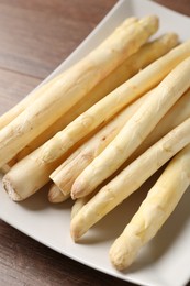 Photo of Raw white asparagus spears on wooden table, closeup