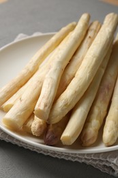 Photo of Raw white asparagus spears on grey textured table, closeup