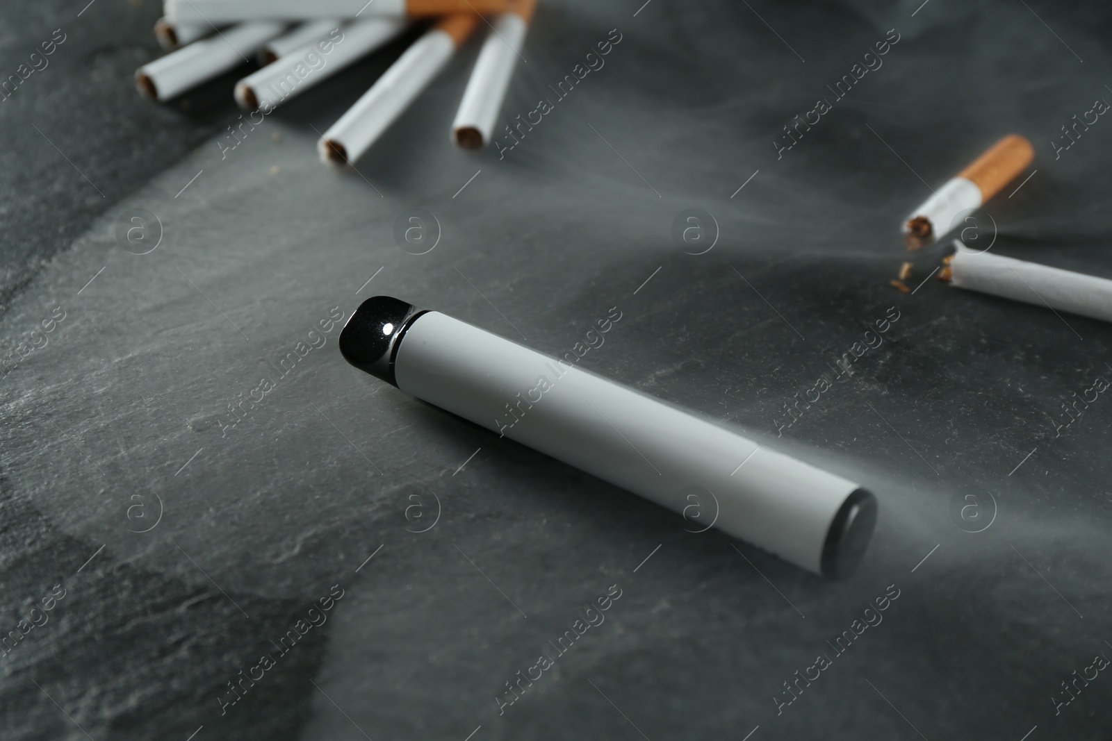 Electronic smoking device and cigarettes on black table, closeup Photo of Electronic smoking device and cigarettes on black table, closeup